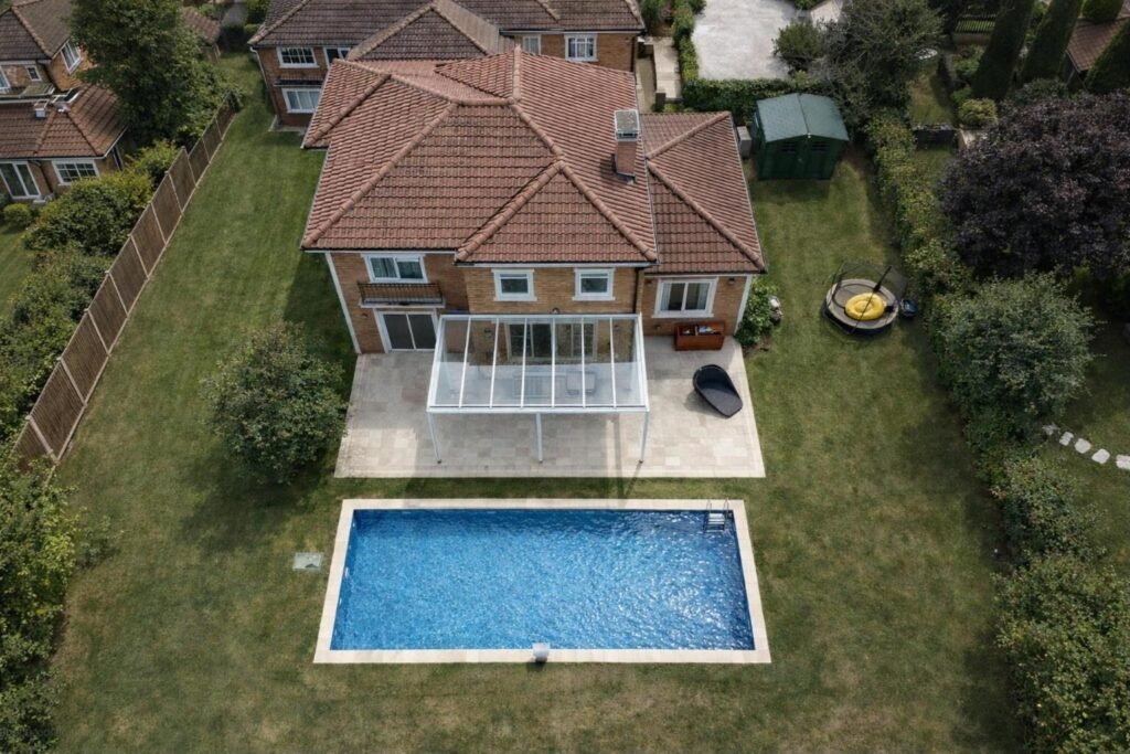 White fixed glass roof veranda over a patio next to a swimming pool, Bowdon, Manchester
